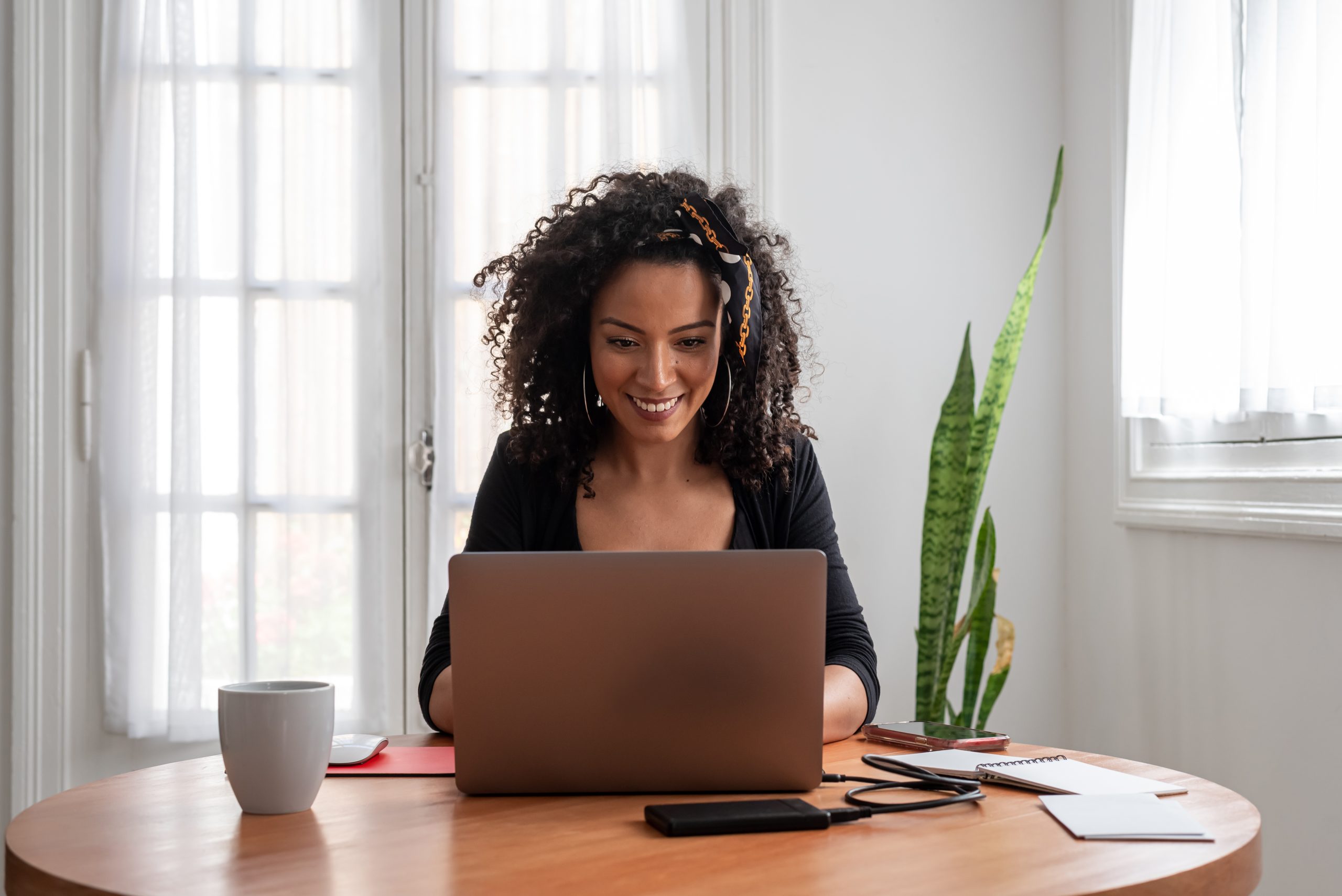 Smiling woman using a laptop at a kitchen table